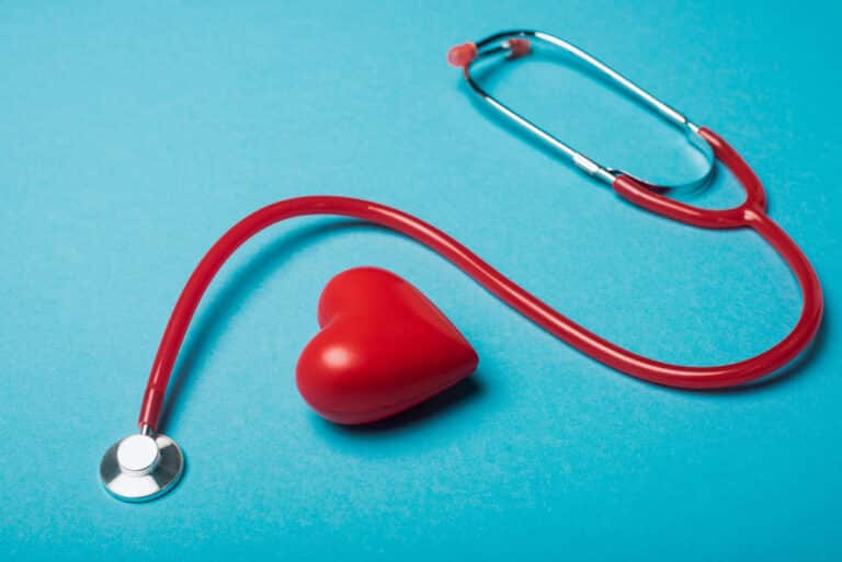 stethoscope and heart-shaped stress reliever on blue background