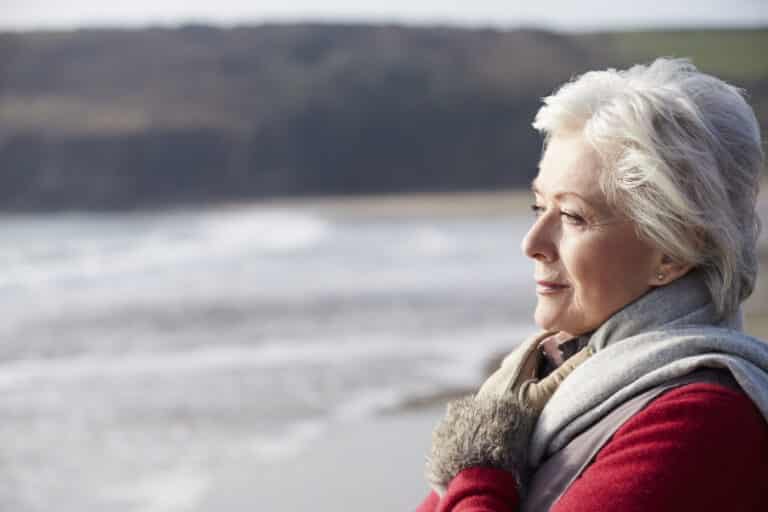 senior woman portrait, looking out at ocean in winter
