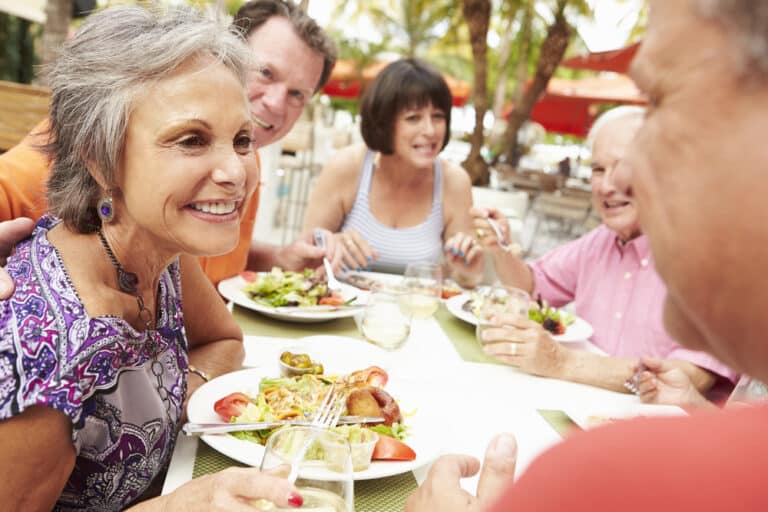 senior friends smiling and enjoying meal at restaurant