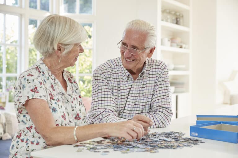 Senior couple smiling and completing puzzle together