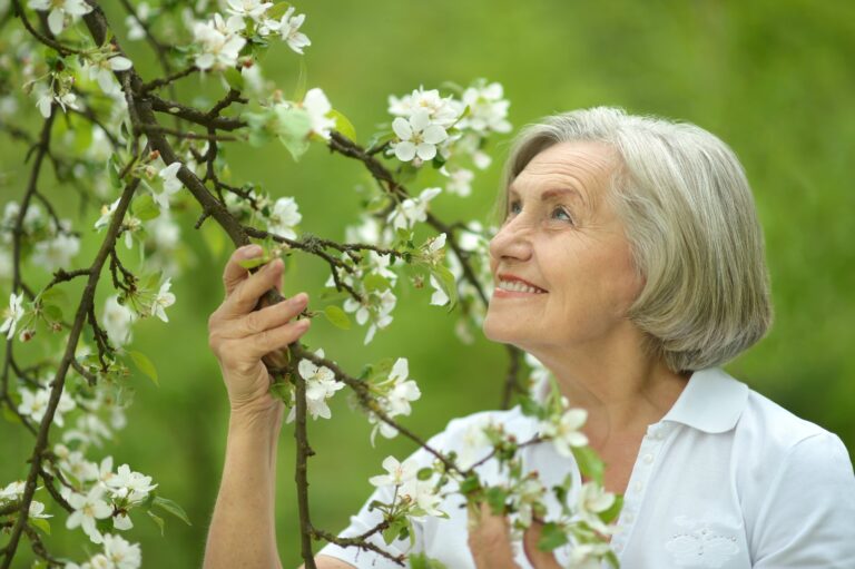 Smiling senior woman beside flowering tree in spring