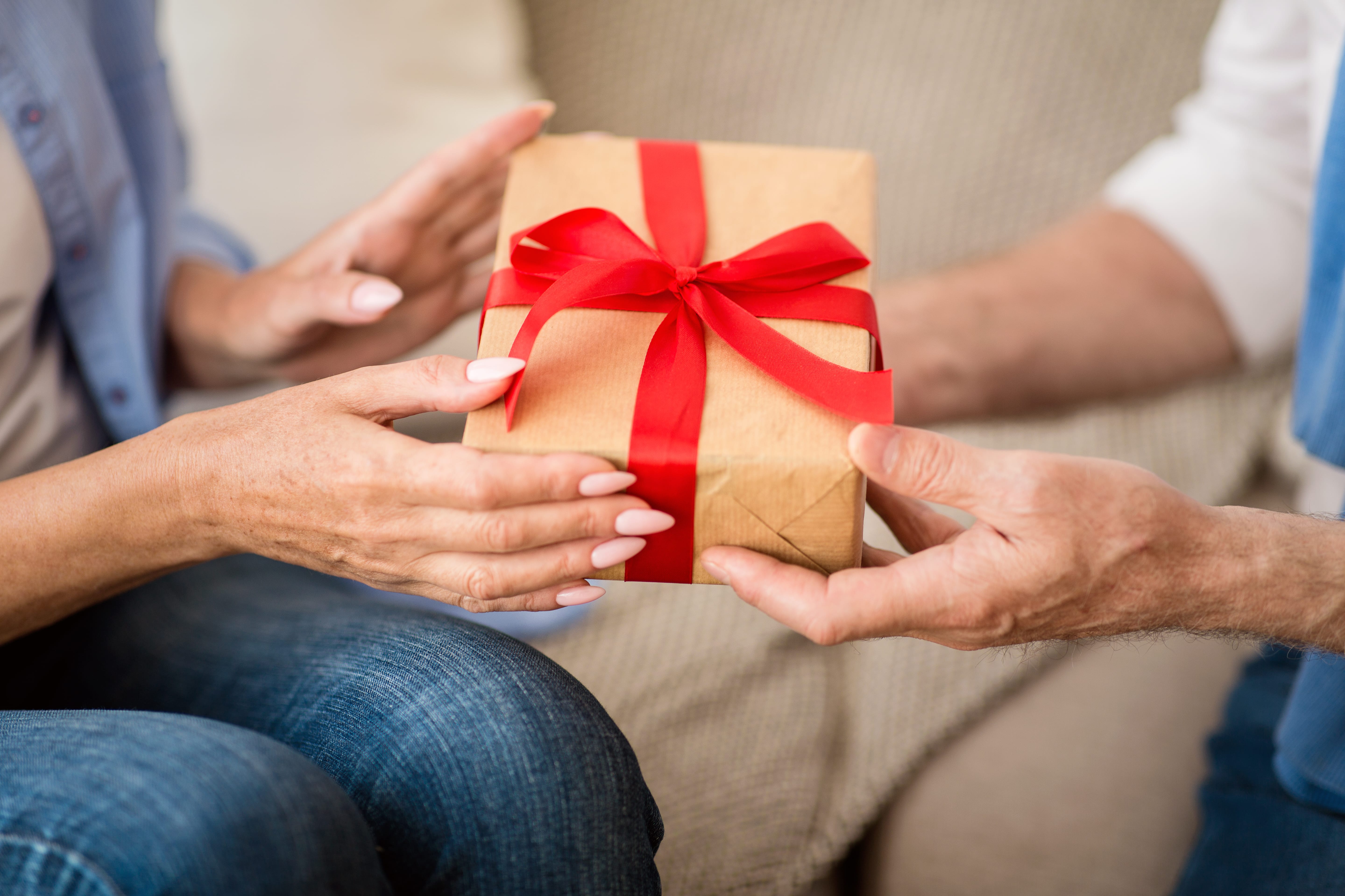 Close-up of adult woman handing gift to senior
