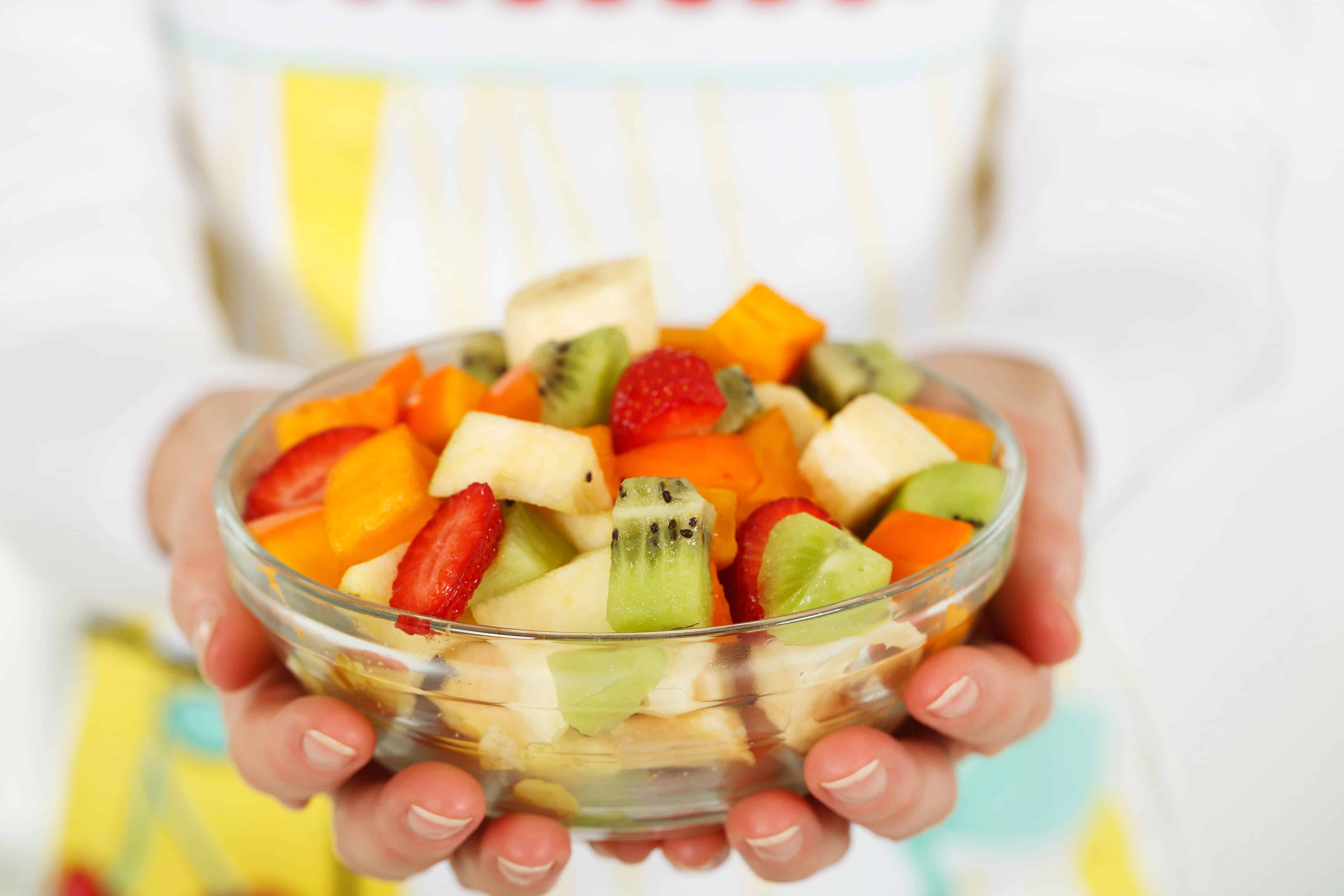 Hands holding bowl of chopped fruit